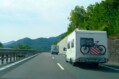 Camper,van,with,bicycle,driving,on,the,highway,across,blue