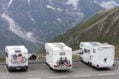 3 motorhomes parked in line next a cliff, facing mountains